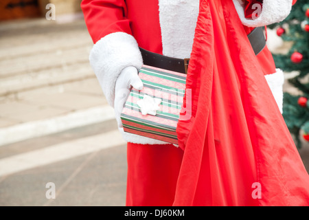 Senior uomo vestito da Babbo Natale regalo mettendo in borsa Foto Stock