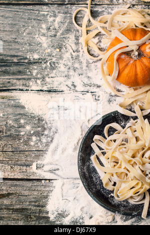 Vista dall'alto su materie pasta fatta in casa con la zucca e farina sopra il vecchio tavolo in legno Foto Stock