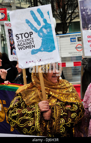 Una donna che indossa abiti tradizionali e una testa sciarpa, tenendo un banner 'stop la violenza contro le donne", London, Regno Unito Foto Stock