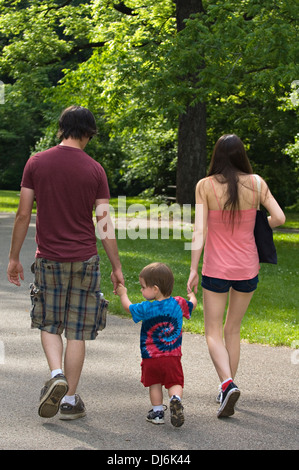 Coppia giovane tenendo le mani del Bambino figlio e passeggiate sul percorso nel mulino a molla del parco statale in Indiana Foto Stock