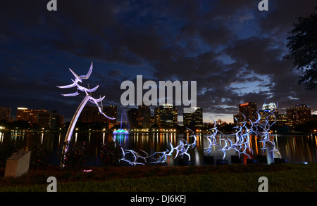 Vedere Arte Scultura Orlando " prendere il volo' dall'artista Douwe Blumberg sul Lake Eola con il centro cittadino di Orlando, Florida edifici. Foto Stock