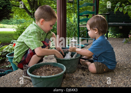 5 anno di età e due anni di Old Boys giocando con il terreno e la Statuetta di rana in vasi di giardinaggio Foto Stock