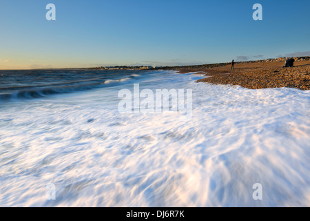 Le onde di colpire la spiaggia su Hurst allo spiedo, Milford-on-Sea, Hampshire al tramonto Foto Stock