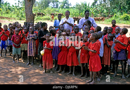 Bambini ugandesi cantare e applaudire un benvenuto ai visitatori per la loro scuola Foto Stock