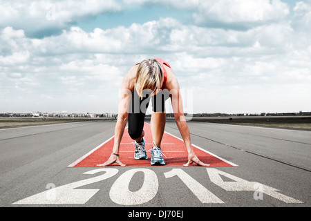 Velocista femmina in attesa per l'avvio su una pista di aeroporto.In primo piano vista prospettica di lettere 2014. Foto Stock