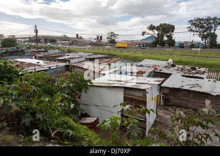 Sud Africa, Cape Town. Guguletu Township a fianco divisa autostrada per l'aeroporto, un piatto di satellite in una baracca sulla destra. Foto Stock