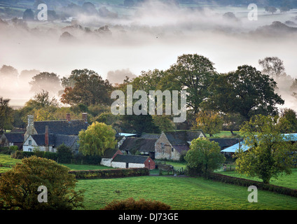 Un agriturismo sembra essere separato dal terreno circostante da bassa nebbia di mattina vicino alla città di Wotton-under-Edge, Gloucestershir Foto Stock