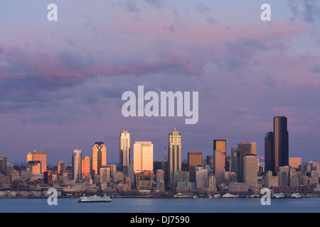 Un traghetto attraversa della Baia di Elliott contro la città di Seattle skyline al tramonto, come visto da ovest a Seattle, Washington. Foto Stock