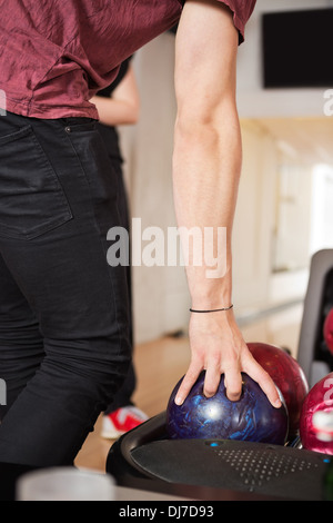 Man Picking palla da bowling dalla cremagliera in Club Foto Stock