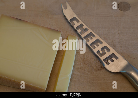 Una fotografia di alcuni formaggi svizzeri con un coltello per formaggio su un tagliere di legno. Si tratta di formaggio gruviera. Foto Stock
