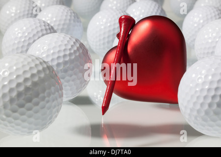 White palline da golf e cuore rosso su un tavolo di vetro Foto Stock