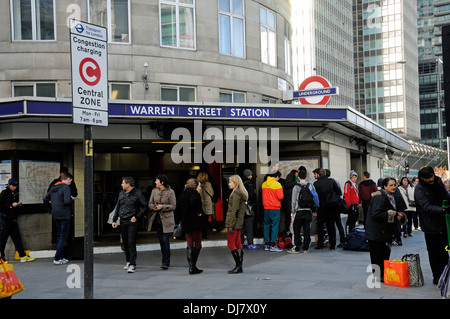 Le persone al di fuori di Warren Street Station con segnale Congestion Charge a sinistra, il centro di Londra Inghilterra REGNO UNITO Foto Stock