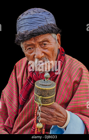 Vecchio bhutanesi buddista uomo pregando isolati su sfondo nero Foto Stock