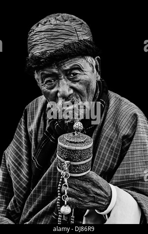 Vecchio Budhhist bhutanesi uomo che prega isolati su sfondo nero, bianco e nero Foto Stock