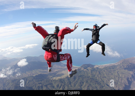 Questo freefly skydiving team di formazione è insieme un sit-battenti la formazione su uno spettacolare scenario di terra nel cielo. Foto Stock