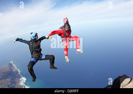 Skydiving Freefly team è la formazione di formazione tenendo le mani in una posizione di sit. Essi divertirsi insieme e sorridente. Foto Stock