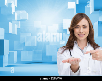 Medico sorridente puntando verso qualcosa in mano Foto Stock