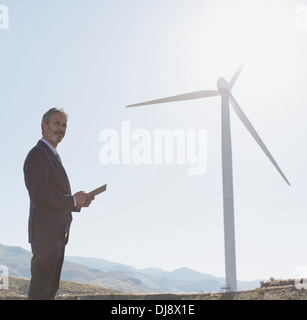Imprenditore ammirando turbina eolica nel paesaggio rurale Foto Stock