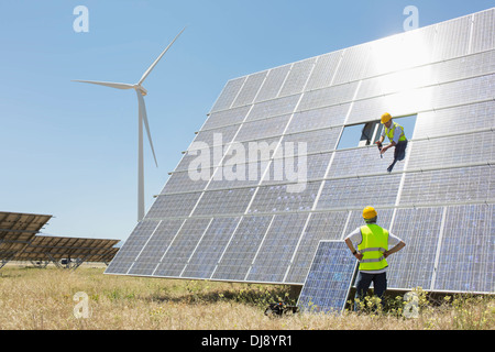 Lavoratori esaminando pannello solare nel paesaggio rurale Foto Stock