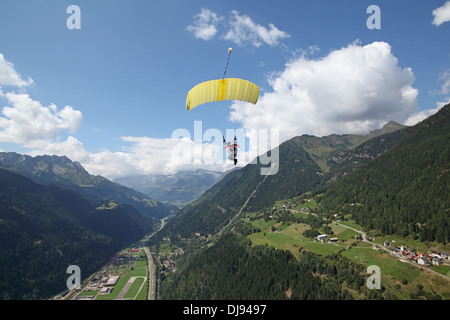 Paracadutista sotto la tettoia è volare alto su alcune montagne tra le nuvole. Tariffa in retro è l'aeroporto a target di atterraggio. Foto Stock