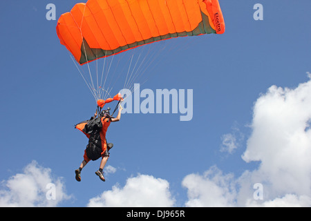 Paracadutista sotto la tettoia è volare alto nel cielo blu tra le nuvole. Prima di lui aveva un salto divertente e aperto salva il paracadute. Foto Stock