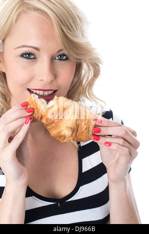 Attraente sorridenti giovane donna Holding e mangiare una cotta stile francese prima colazione continentale Croissant contro uno sfondo bianco Foto Stock