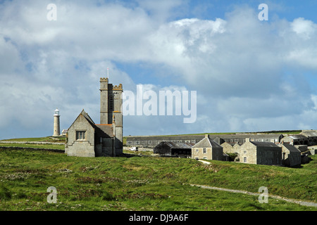 Cluster di edifici su Lundy Island, Devon, Inghilterra. St Helena la Chiesa in primo piano. Il vecchio faro di luce è in distanza. Foto Stock