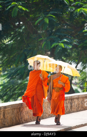 I giovani monaci novizio a piedi lungo la riva del fiume Nam Khan a Luang Prabang, Laos Foto Stock