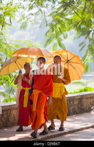 I giovani monaci novizio a piedi lungo la riva del fiume Nam Khan a Luang Prabang, Laos Foto Stock