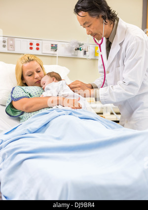 Medico esaminando Babygirl dorme nella Madre di braccia Foto Stock