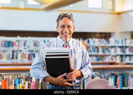 L'uomo anziano con libri in biblioteca Foto Stock