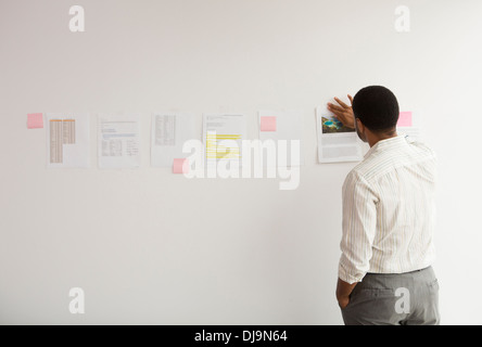 Imprenditore nero con nastro adesivo di carta sulla parete per ufficio Foto Stock