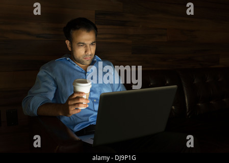 Uomo d affari con computer portatile sul divano di notte Foto Stock