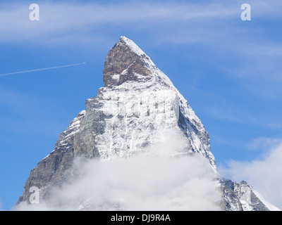 La sommità del picco alpino del Cervino in Svizzera contro il cielo blu, trafitto da un piano che passa alto sopra Foto Stock