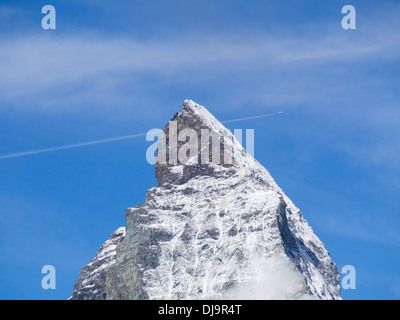 La sommità del picco alpino del Cervino in Svizzera contro il cielo blu, trafitto da un piano che passa alto sopra Foto Stock