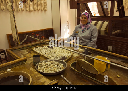 Bozzoli di seta, cotone, tappeti, donna seduta Foto Stock