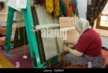 Donna filettatura di lavoro tessitura su un telaio per un tappeto in Turchia Foto Stock