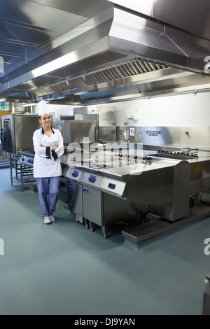 Giovani chef felice in piedi accanto alla superficie di lavoro Foto Stock