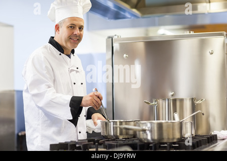 Sorridente capo chef agitazione in pentola Foto Stock