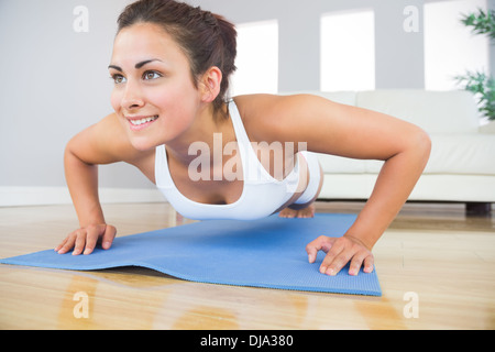 Montare la giovane donna facendo premere ups su un tappeto di esercizio Foto Stock