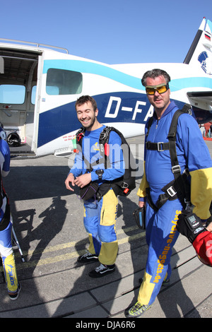 Questi skydivers stanno entrando il velivolo insieme e il passeggero è molto felice di andare per un salto in tandem. Foto Stock