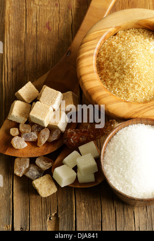 Diversi tipi di zucchero - marrone, bianco, zucchero raffinato su uno sfondo di legno Foto Stock