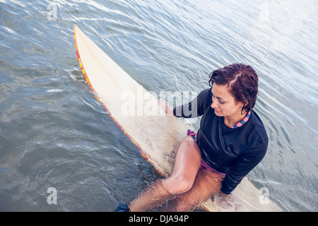 Bella donna seduta sulla tavola da surf in acqua Foto Stock