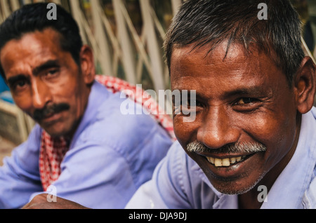 Due lavoratori immigrati si prendono una pausa dalle fatiche nelle strade di Deira. Dubai, Emirati Arabi Uniti. Foto Stock