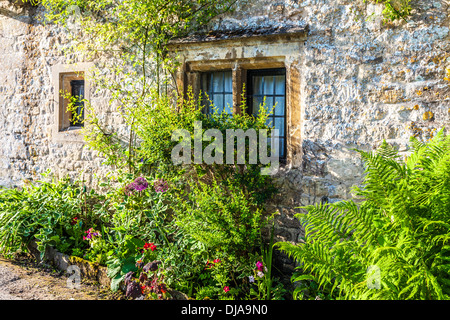 Luce con piombo finestra e giardino anteriore nel famoso Arlington fila di tessitori' case di villaggio Costwold di Bibury. Foto Stock