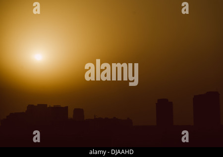 Il sole tramonta dietro uno spesso strato di sabbia nell'orizzonte a Dubai Media City. Dubai, Emirati Arabi Uniti. Foto Stock