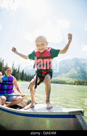 Ragazzo caucasico permanente sulla canoa sul lago Foto Stock