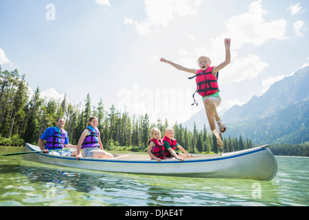 Ragazzo caucasico saltando dalla canoa nel lago Foto Stock