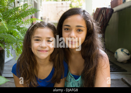 Razza mista sorelle seduti all'aperto Foto Stock