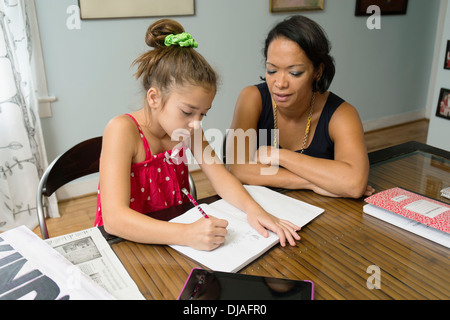 Razza mista madre aiutare mia figlia con i compiti Foto Stock